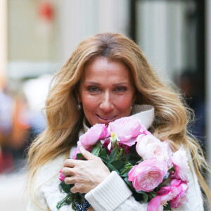Celine Dion rayonnante et très souriante dans un ensemble pull écru et jupe bouffante fleurie salue ses fans à la sortie de son hôtel à New York, le 8 mars 2020 