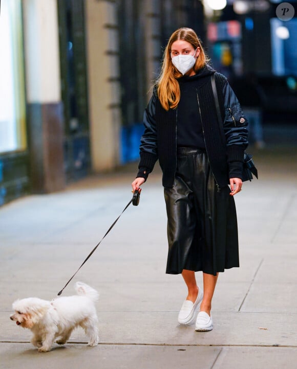 Exclusif - Olivia Palermo promène son chien M. Butler le soir à Brooklyn, New York le 21 octobre 2020. Elle porte un masque facial, une veste Moncler, un sweat à capuche noir, une jupe en cuir et des mocassins blancs.