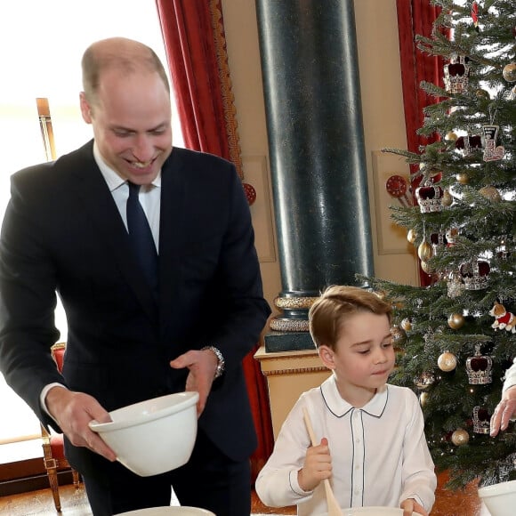 Le prince George de Cambridge prépare, sous le regard bienveillant du prince William, duc de Cambridge, du prince Charles, prince de Galles et de la reine Elisabeth II, des puddings de Noël, dans le cadre du lancement de l'initiative 'Together at Christmas' de la Royal British Legion au Palais de Buckingham, le 21 décembre 2019. 