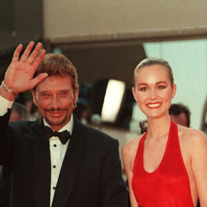 Johnny Hallyday fait partie des rares stars à avoir monté les marches avec trois femmes différentes à son bras.
Johnny Hallyday et son épouse Laeticia arrivent au Palais des Festivals à Cannes, pour l'ouverture du film 'Primary Colours' au 51ème Festival de Cannes, France, 1998. Photo par Neil Munns/PA Photos/ABACAPRESS.COM