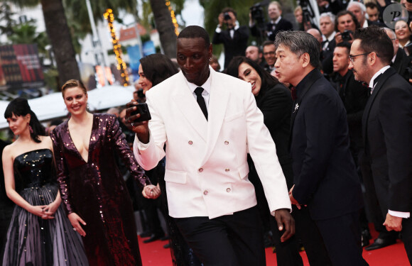 L'acteur d'''Intouchables'' a agacé ses détracteurs en osant faire une série de selfies avec ses amis sur le tapis rouge.
L'acteur français Omar Sy (devant), également membre du jury de la 77e édition du Festival de Cannes, apparaît sur le tapis rouge de la cérémonie d'ouverture du festival à Cannes, dans le sud de la France, le 14 mai 2024.