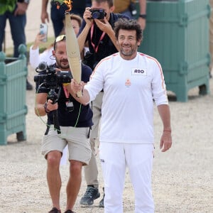 Le chanteur et acteur Patrick Bruel porteur de la flamme olympique des Jeux Olympiques de Paris 2024 (JO) au château de Versailles dans les Yvelines, France, le 23 juillet 2024. © Dominique Jacovides/Bestimage