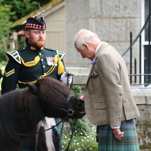 Le roi Charles III d'Angleterre, accueilli par des soldats de la compagnie Balaklava, 5e bataillon du Royal Regiment of Scotland devant le château de Balmoral (Ecosse), où le souverain débute ses vacances d'été, le 19 août 2024.