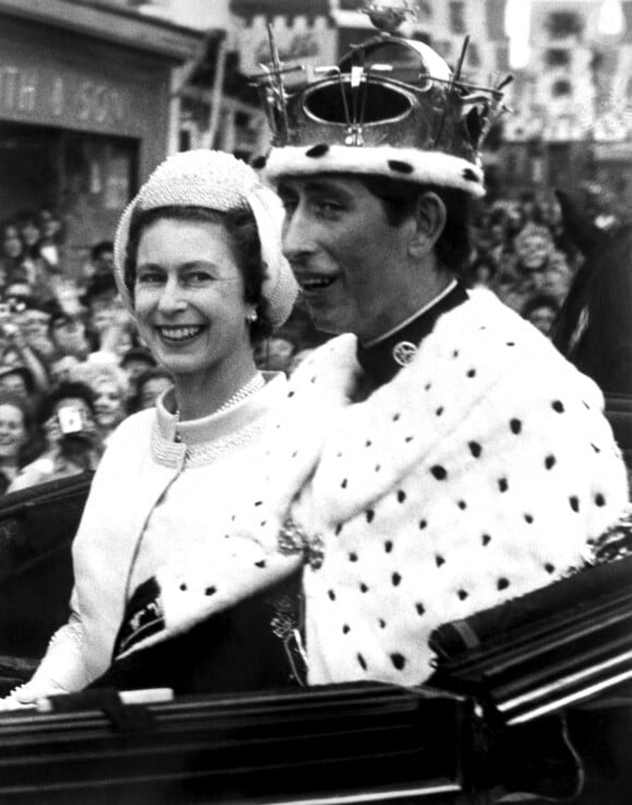 De plus, la "requête inclut une demande d'autorisation de vendre de l'alcool et de jouer de la musique jusqu'à minuit et demi".
La Reine Elizabeth II jette un rapide coup d'oeil à son fils, le Prince Charles, heureux et souriant, alors que leur caravane d'État quitte le château de Caernarvon cet après-midi, après l'investiture de Charles en tant que Prince de Galles, 1969. 