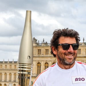 Le chanteur et acteur Patrick Bruel porteur de la flamme olympique des Jeux Olympiques de Paris 2024 (JO) au château de Versailles dans les Yvelines, France, le 23 juillet 2024. © Dominique Jacovides/Bestimage 