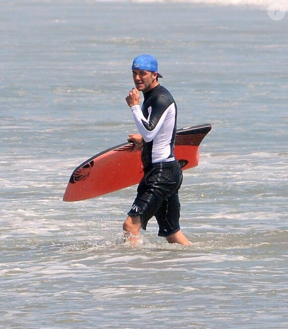 David Beckham ne quitte pas sa casquette bleue pour surfer à Malibu, le 30 juillet 2011.