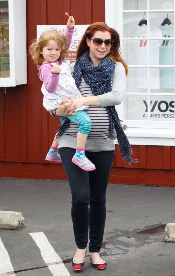 Alyson Hannigan, souriante avec sa fille Satyana dans les bras, au cours d'un après-midi shopping à Los Angeles, le 25 avril 2012.
