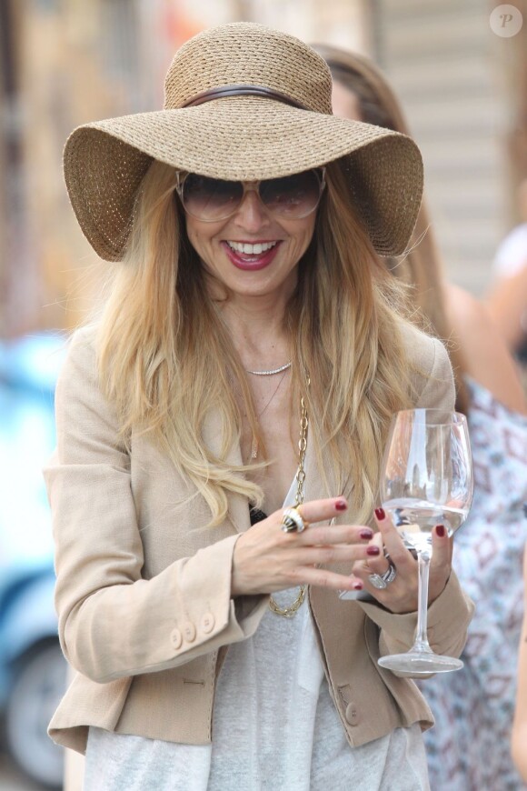 Réputée aigrie et maniérée, Rachel Zoe est tout sourire avec un verre d'eau et son téléphone dans la main à New York. Le 8 juin 2012.