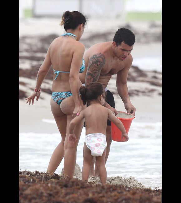 Carlos Tévez en compagnie de sa femme Vanessa Mansilla et de sa fillette Katia, en plein construction d'un château de sable le 25 juin 2012 à Miami