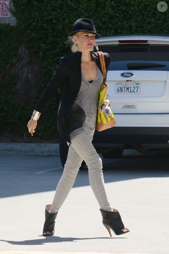 Gwen Stefani porte un blazer sans col Theyskens Theory sur un t-shirt oversize gris et un pantalon à imprimé léopard. Une tenue accessoirisée d'un chapeau, d'une manchette argentée, de bottines Maison Martin Margiela et d'un sac fluo L.A.M.B. Los Angeles, le juillet 2012.