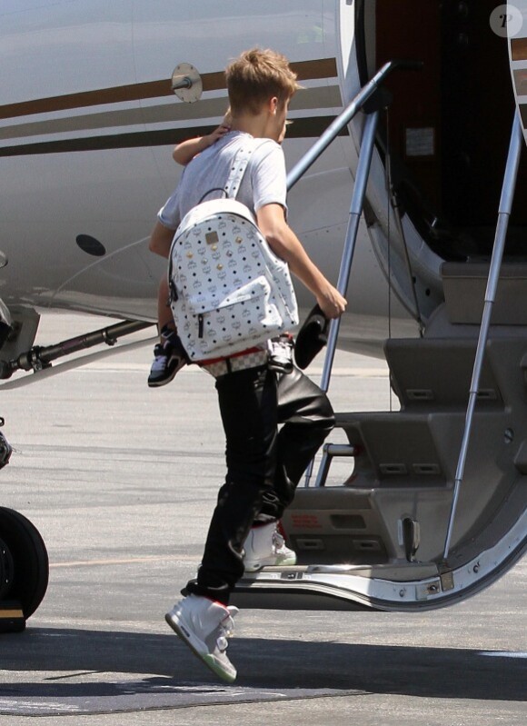 Justin Bieber prend son rôle de grand frère très à coeur alors qu'il embarque dans un jet privé avec son petit frère Jaxon dans les bras à Van Nuys le 1er août 2012
