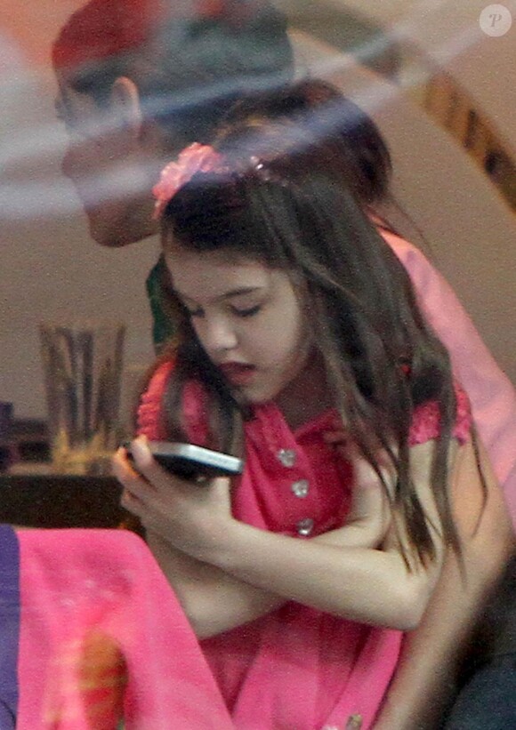 Suri squatte le téléphone de maman sur les genoux de Katie Holmes au Sugar & Plumm de Manhattan, le 18 décembre 2012.