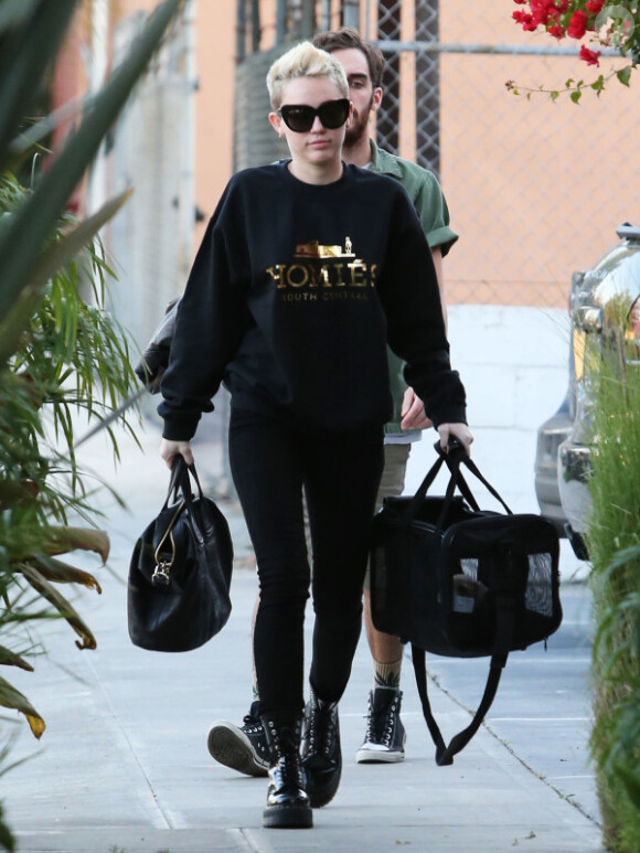 Miley Cyrus, de noir vêtue, accompagnée de son nouveau petit chien, se rendant en studio d'enregistrement à Burbank (Californie), le 4 janvier 2013.