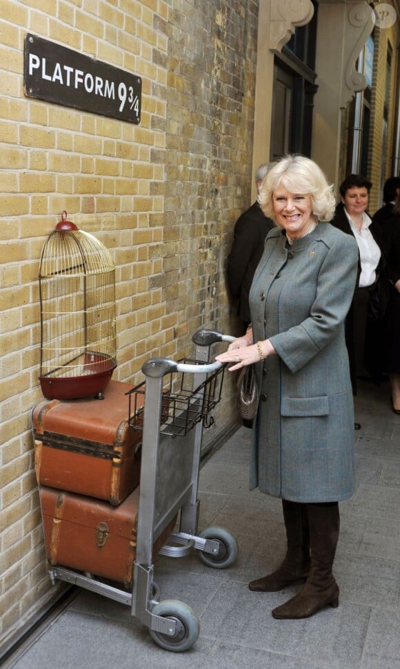 Le prince Charles et Camilla Parker Bowles devant un décor inspiré de la saga Harry Potter à Kings Cross Station dans le cadre de leur visite dans le métro de Londres le 30 janvier 2013, à l'occasion du 150e anniversaire du réseau en 2013.