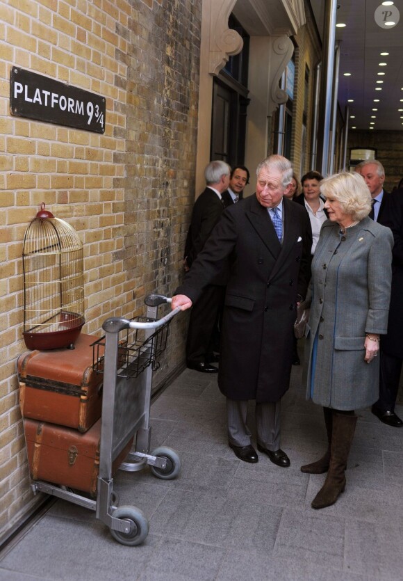 Le prince Charles et Camilla Parker Bowles devant un décor inspiré de la saga Harry Potter à Kings Cross Station dans le cadre de leur visite dans le métro de Londres le 30 janvier 2013, à l'occasion du 150e anniversaire du réseau en 2013.