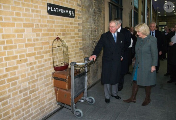 Le prince Charles et Camilla Parker Bowles devant un décor inspiré de la saga Harry Potter à Kings Cross Station dans le cadre de leur visite dans le métro de Londres le 30 janvier 2013, à l'occasion du 150e anniversaire du réseau en 2013.