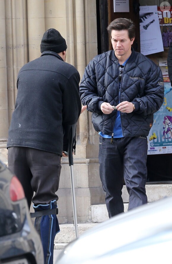 Mark Wahlberg s'apprête à donner de l'argent à un mendiant présent devant la Cathédrale américaine de la Sainte Trinité à Paris, le 3 février 2013.