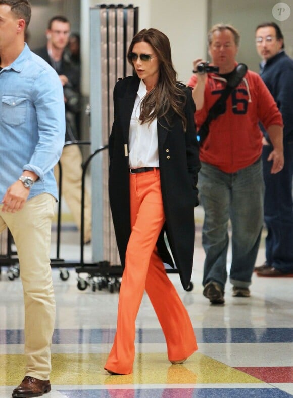 Victoria Beckham twiste son look notamment composé d'un manteau Victoria Beckham et de sandales Chloé avec un pantalon orange. New York, le 8 mai 2013.