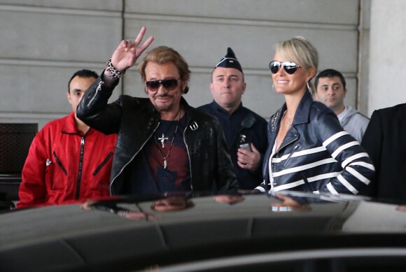 Avant de monter dans leur voiture, Johnny et Laeticia Hallyday saluent une dernière fois les badauds, à l'aéroport de Paris, le 21 mai 2013.