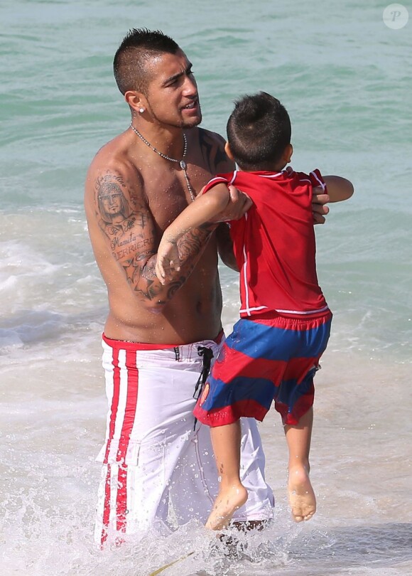 Arturo Vidal porte son fils Alonso dans ses bras musclés lors d'une journée ensoleillée sur la plage de Miami, le 29 Juin 2013
