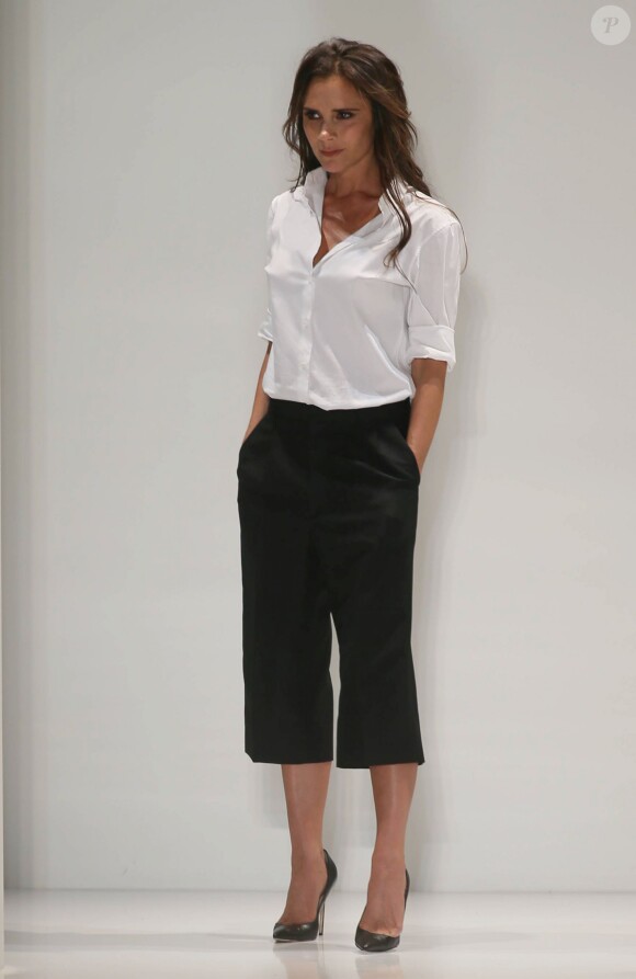 Victoria Beckham, ultra chic en chemise blanche, pantalon noir et souliers Manolo Blahnik, salue son public à l'issue de son défilé printemps-été 2014. New York, le 8 septembre 2013.