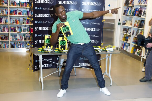 Usain Bolt prend sa célèbre pose lors de la signature de son autobiographie Faster than Lightning chez WHSmith à Londres le 19 septembre 2013