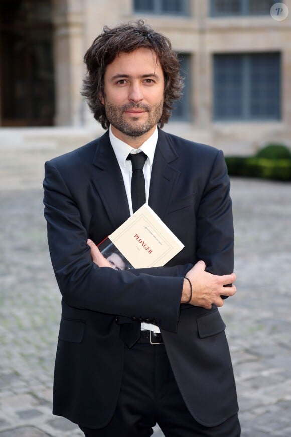 L'écrivain et journaliste Christophe Ono-dit-Biot pose avec son livre "Plonger"qui vient de lui valoir Grand prix du roman de l'Académie française à Paris, le 24 Octobre 2013.
