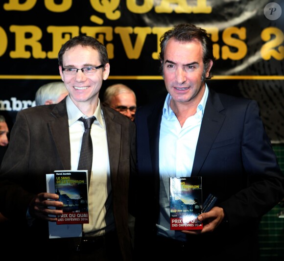 Jean Dujardin et le lauréat lors de la remise du prix polar Quai des Orfèvres 2014 à Hervé Jourdain, capitaine à la Crim', pour son livre Le sang de la trahison, à Paris, le 12 novembre 2013.