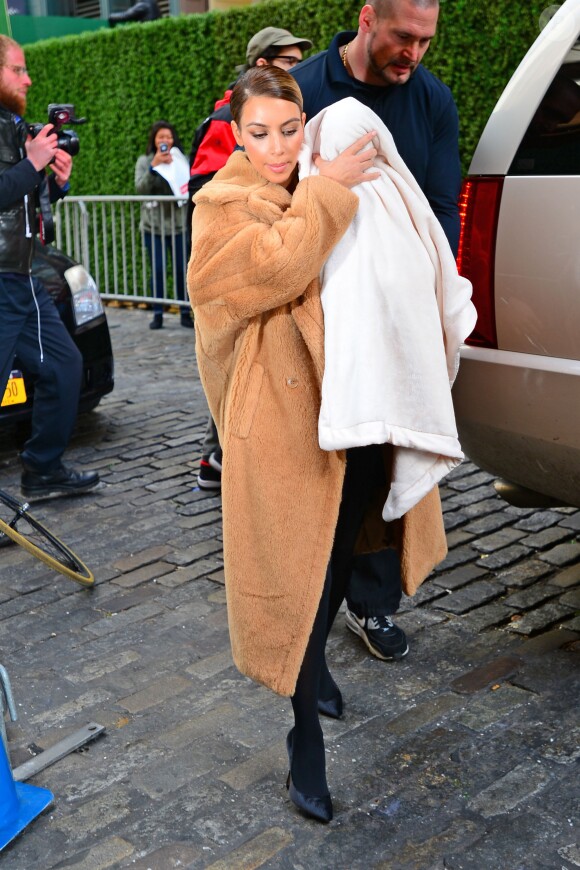 Kim Kardashian, stylée dans un manteau Max Mara, et sa fille North au chaud dans une petite couverture, ont provoqué une mini-émeute dans le quartier de SoHo. New York, le 19 novembre 2013.