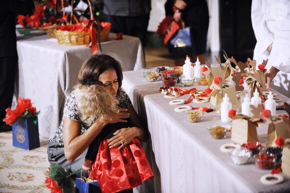 Michelle Obama embrasse la petite Ashtyn Gardner, 2 ans, lors de la présentation des décorations de Noël de la Maison Blanche. Washington, le 4 décembre 2013.