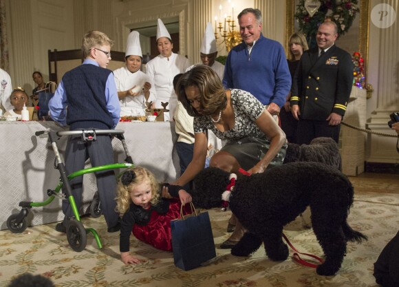 Michelle Obama relève et rassure l'adorable Ashtyn Gardner (2 ans), chahutée par son chien Sunny lors de la présentation des décorations de Noël de la Maison Blanche. Washington, le 4 décembre 2013.