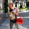 Hilary Duff, radieuse à Los Angeles, porte un sac rouge Louis Vuitton (modèle Speedy 25) avec un débardeur, un slim gris et des bottines Jimmy Choo (modèle Talma). Le 16 septembre 2013.