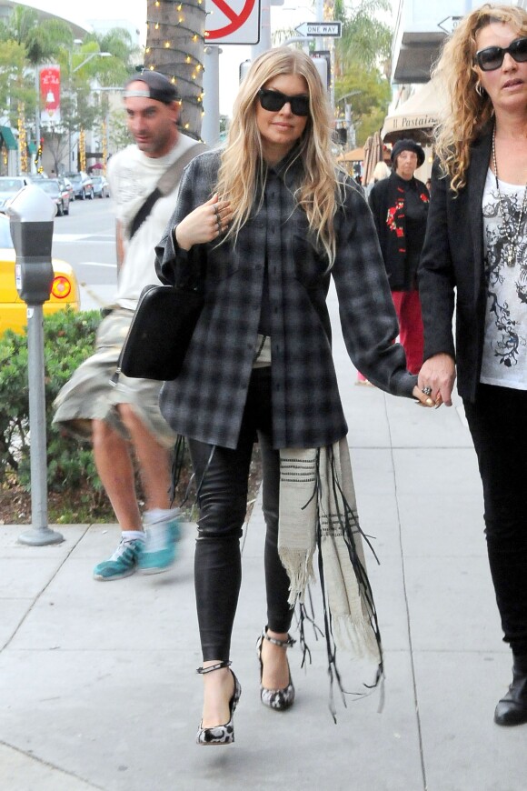 Fergie en pleine séance shopping à Beverly Hills, porte des lunettes et une pochette Céline, une chemise à carreaux grise et noire Saint Laurent, un pantalon en cuir et des souliers Christopher Kane (pré-collection automne 2013). Le 17 décembre 2013.