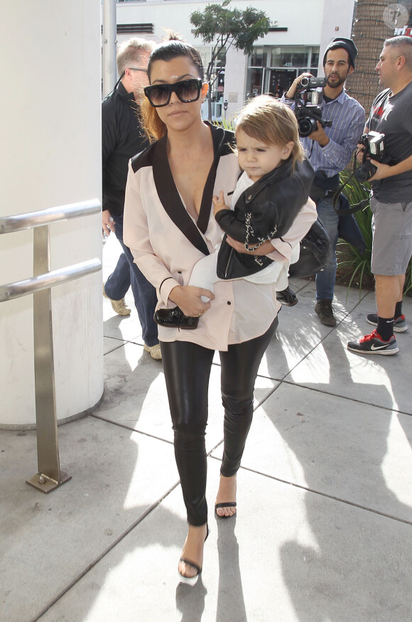 Kourtney Kardashian, maman stylée avec sa fille Penelope à Beverly Hills, porte des lunettes Céline, un chemisier décolleté Asos, un pantalon en cuir, un sac Chanel et des sandales Alexander Wang (modèle Antonia). Los Angeles, le 16 décembre 2013.