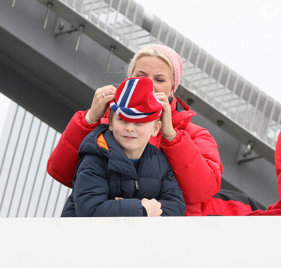 La princesse Mette-Marit de Norvège veille à ce que son fils le prince Sverre Magnus soit bien couvert, à Holmenkollen le 9 mars 2014 pour la Coupe du monde de saut à ski.
