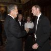 Le prince William salue Mario Testino, le 13 mai 2014 au château de Windsor, lors d'une soirée de bienfaisance au profit du Royal Marsden Hospital dont le duc de Cambridge est le président, organisée avec Ralph Lauren.
