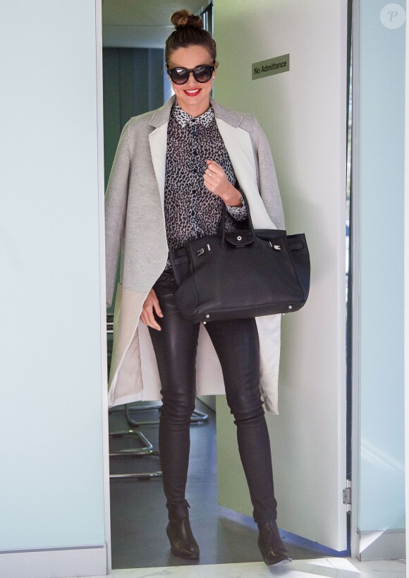 Miranda Kerr quitte les bureaux de Kora Organics, sa marque de produits de beauté, habillée d'un manteau gris et blanc, d'une chemise léopard et de bottines Saint Laurant, d'un pantalon en cuir Genetic et d'un sac Hermès. Sydney, le 16 mai 2014.