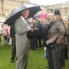 Le prince Charles discute avec des invités lors de la pluvieuse troisième garden party de l'année organisée à Buckingham Palace le 3 juin 2014.
