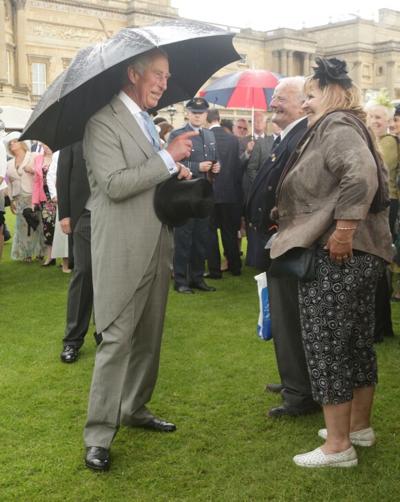 Le prince Charles discute avec des invités lors de la pluvieuse troisième garden party de l'année organisée à Buckingham Palace le 3 juin 2014.