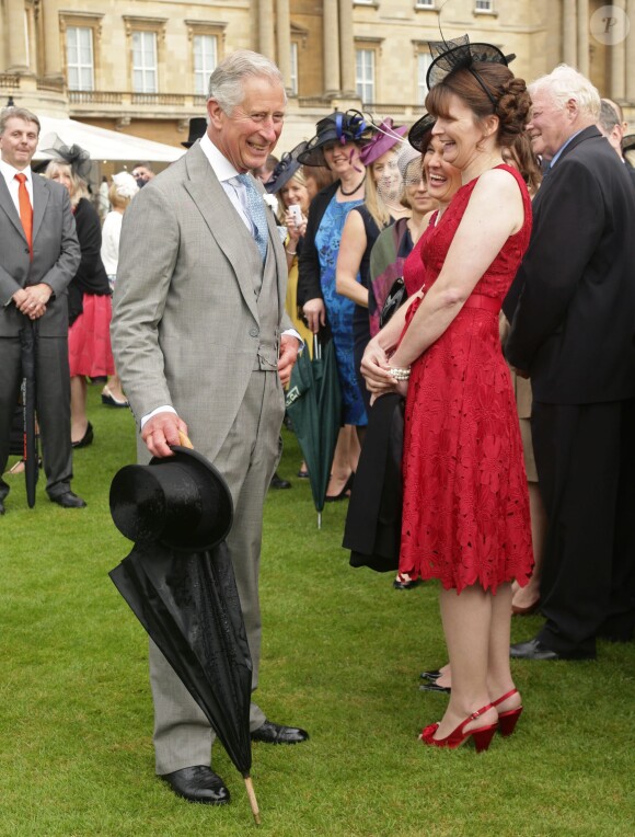 Le prince Charles profite d'une éclaircie pour ranger son parapluie lors de la pluvieuse troisième garden party de l'année organisée à Buckingham Palace le 3 juin 2014.