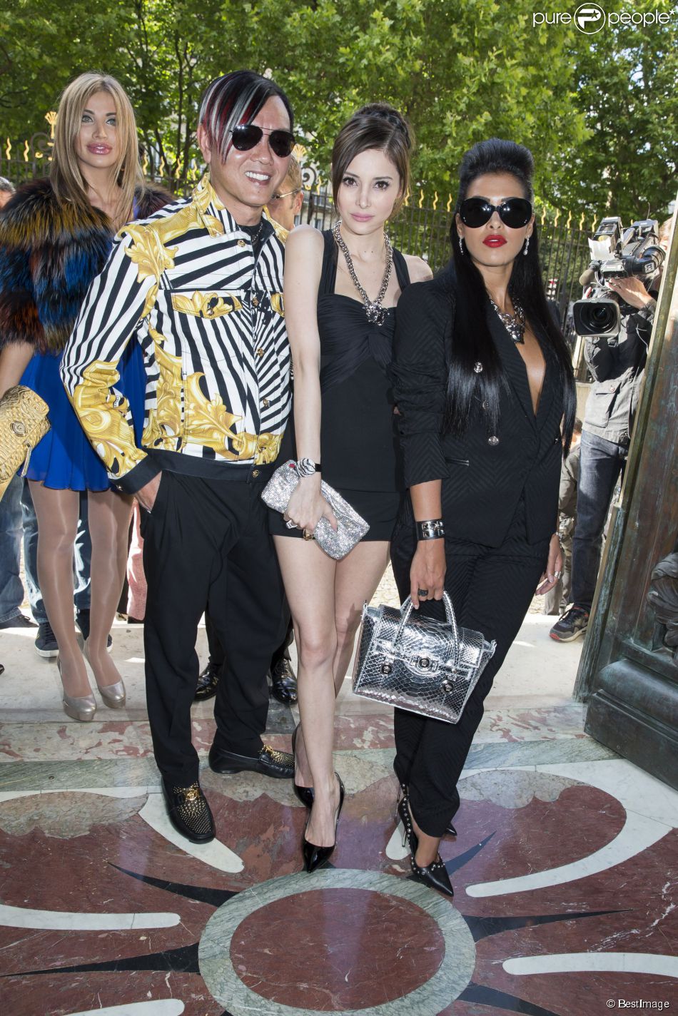 Ayem Nour, en élégante compagnie lors du défilé haute couture Versace automne-hiver 2014-2015. Paris, le 6 juillet 2014.