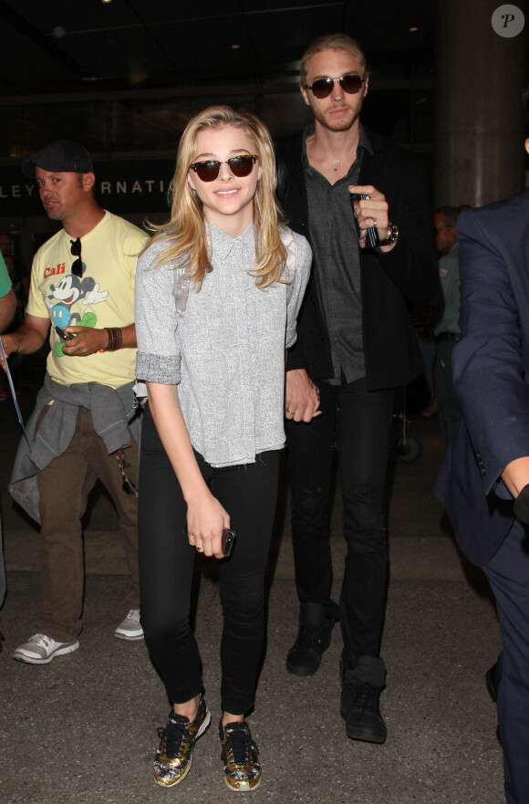 Chloë Grace Moretz arrive à l'aéroport de Los Angeles avec son frère Trevor, habillée de lunettes Ray-Ban, d'un sac à dos (collection prêt-à-porter printemps-été 2014) et de baskets Chanel. Le 10 juillet 2014.