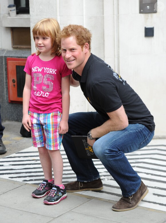 Le prince Harry pose avec la jeune Olivia Hanhock en sortant de la BBC Radio 2 le 30 juillet 2014 après avoir enregistré une interview pour les Invictus Games.