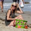 Tori Spelling joue avec ses enfants Stella, Hattie, et Finn sur une plage de Malibu, le 25 juillet 2014.