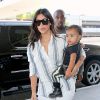Kim Kardashian à l'aéroport de Los Angeles avec Kanye West et leur fille North, porte un chemisier rayé, un jean blanc et des sandales Hermès. Le 1er septembre 2014.