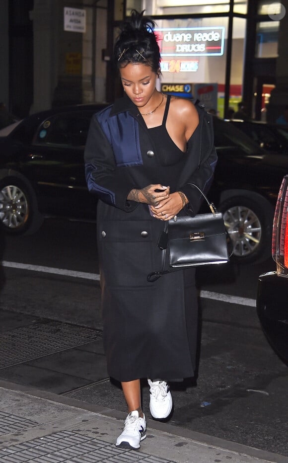 Rihanna à New York, porte un manteau Miu Miu, une petite robe noire Reformation, un sac Balenciaga (modèle Le Dix Cartable) et des baskets New Balance. Le 23 septembre 2014.