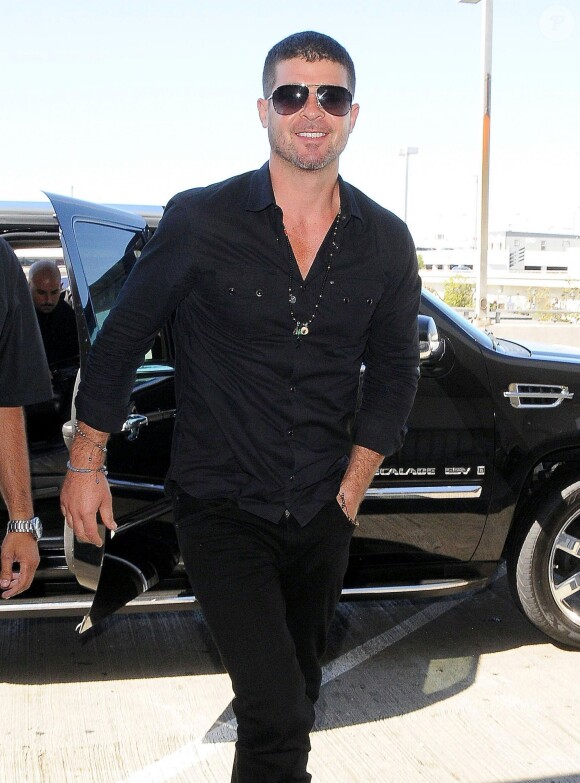 Robin Thicke arrive, tout souriant, pour prendre un avion à l'aéroport de LAX à Los Angeles, le 14 août 2014.