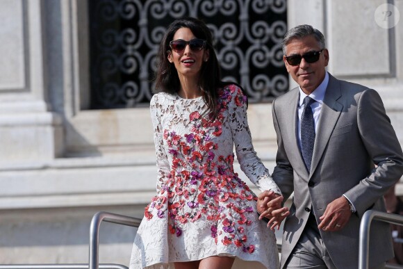 George Clooney et Amal Alamuddin (en Giambattista Valli), portant leurs alliances, apparaissent pour la première fois après leur mariage, le 28 septembre 2014, quittant l'Aman Grande Canal Venice après leur nuit de noces pour rallier le Cipriani pour un brunch avec leurs proches.