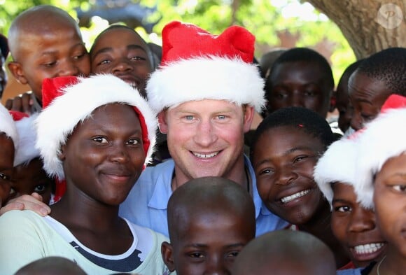 Le prince Harry, coiffée d'un bonnet de Noël malgré les 32 degrés, posant avec des orphelins du foyer Mants'ase Children's Home de Maseru au Lesotho le 5 décembre 2014 lors de sa visite privée pour suivre les actions de son association Sentebale.