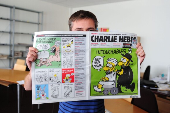 Charb de Charlie Hebdo prend la pose avec le journal à Paris, en 2012.